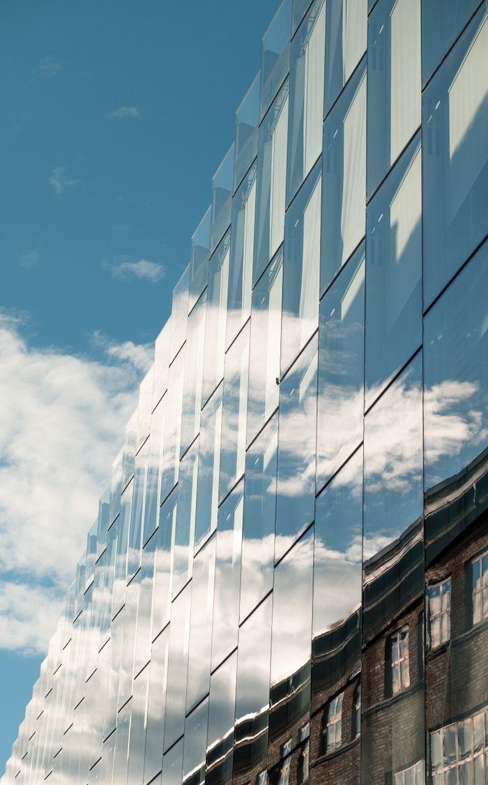 Glass building reflecting the sky and surrounding architecture in Oslo, Norway.