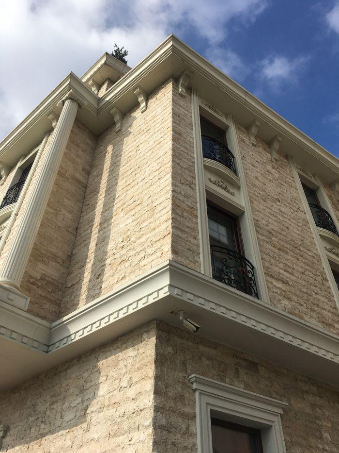 Low angle view of a classical stone building with ornate architectural details and blue sky.